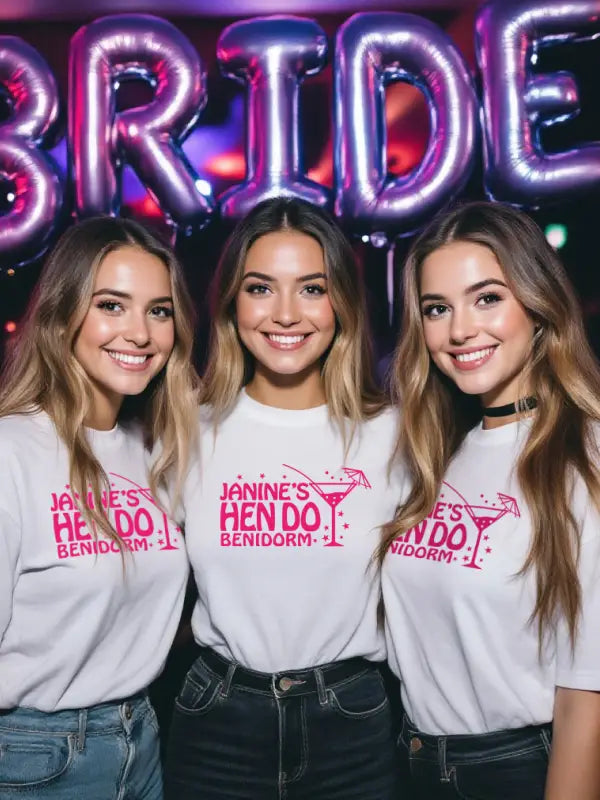 Three women in matching white T-shirts with neon pink hen do iron on transfers in Benidorm.