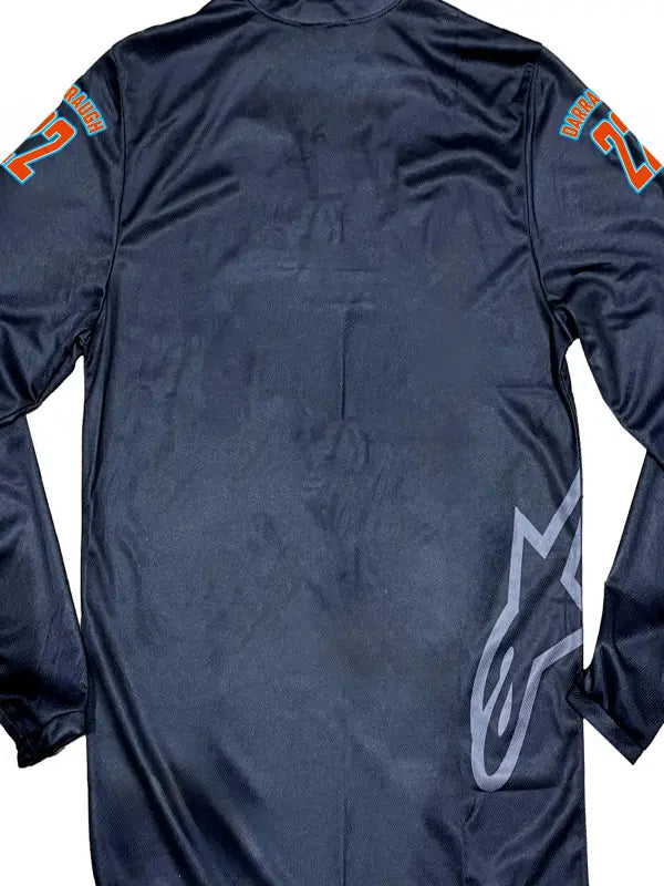 Close-up of a black motocross jersey featuring arms only in bright orange iron on transfers.
