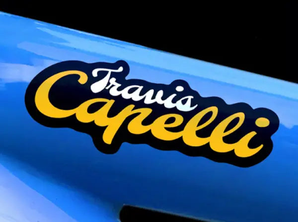 Glossy blue frame featuring a personalised bike sticker reading ‘Travis Capelli’ in bold yellow and white script with black outline.