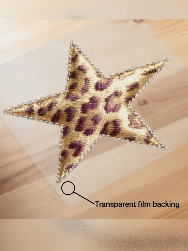 Leopard print iron on star transfer placed on transparent film backing on a wooden surface, ready for heat application.