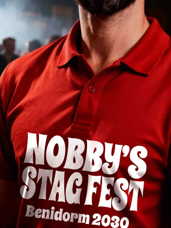 Red polo shirt with 'Nobby's Stag Fest Benidorm 2030' text on a blurred background