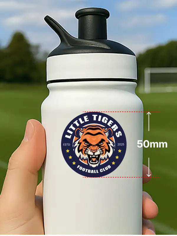 Hand holding bottle with 50mm personalised bottle sticker showing Little Tigers football club badge on white bottle.

